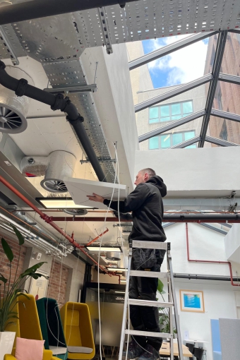 Installing ceiling microphones in multipurpose meeting space..