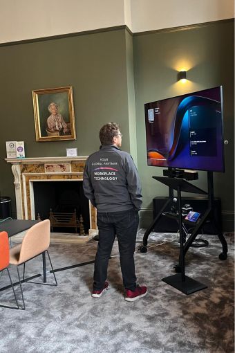 Audio visual technician observing display screen in BVA large multipurpose meeting room, London.