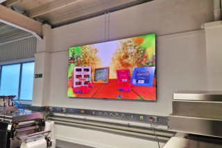 Large LED screen showing brightly coloured packaged products at Multivac Innovation centre.